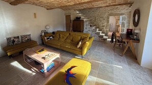 Un soggiorno accogliente con un divano giallo, un tavolino in legno e una scala che conduce a un piano superiore.
