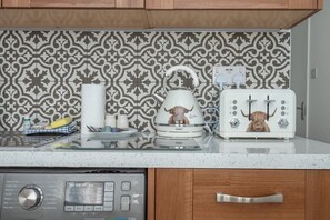 A kitchen with a patterned backsplash, a coffee machine, a toaster, and a dishwasher. - Hackney Central | London Fields & Broadway Market (London)