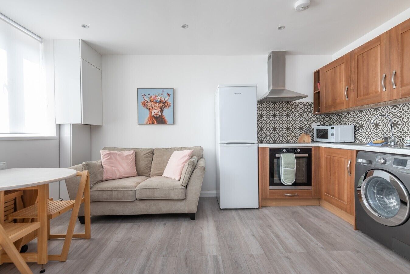 Eine kleine Küche mit Sofa, Waschmaschine, Mikrowelle und Kühlschrank.
