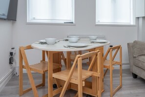 Ein runder Holztisch mit vier Stühlen, weißen Tellern, Schüsseln und Besteck.