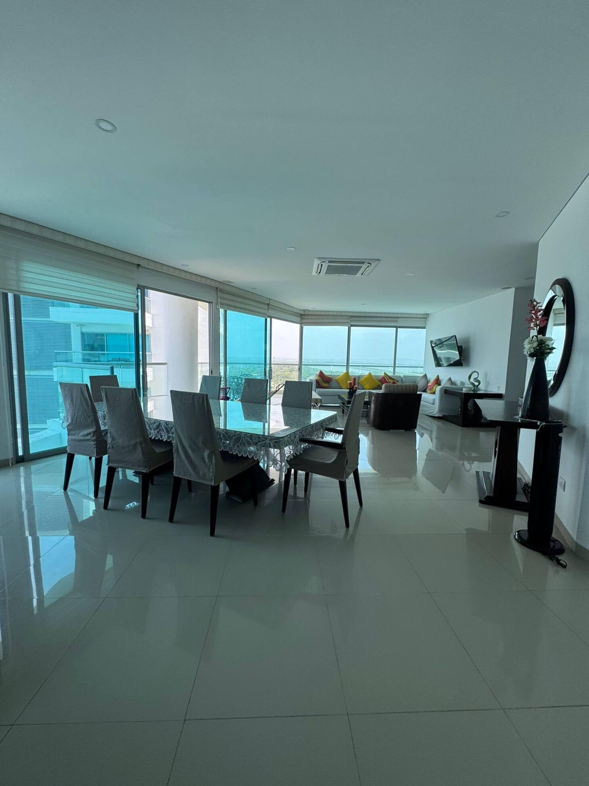 Una sala de estar moderna con comedor, ventanas amplias y vista al mar.