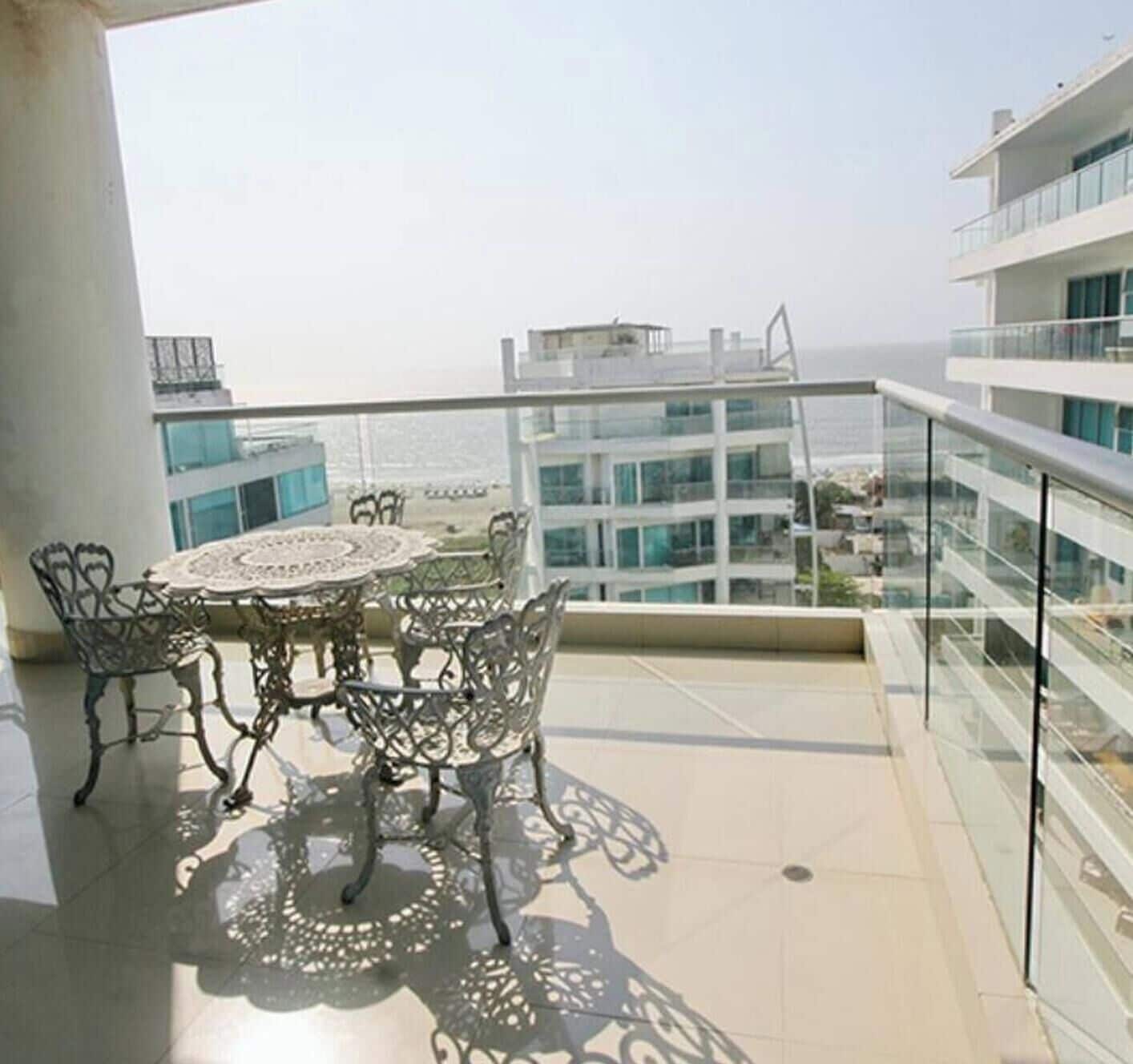 A balcony with a table and chairs, overlooking a cityscape.