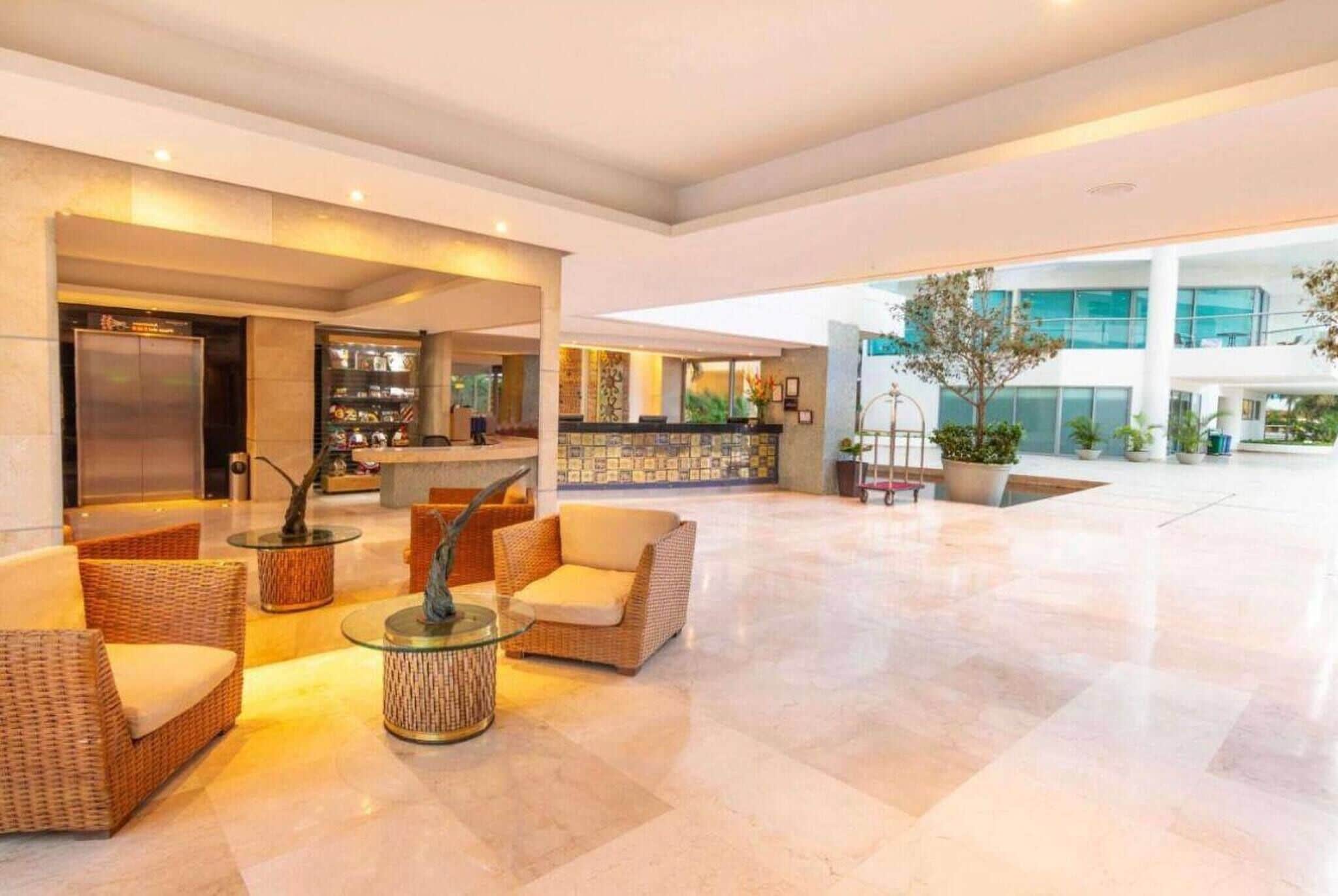 Un vestíbulo amplio con mostrador de recepción, zona de estar y un gran espacio abierto con vista al exterior del edificio.