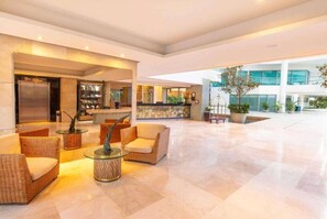 Un vestíbulo amplio con mostrador de recepción, zona de estar y un gran espacio abierto con vista al exterior del edificio.