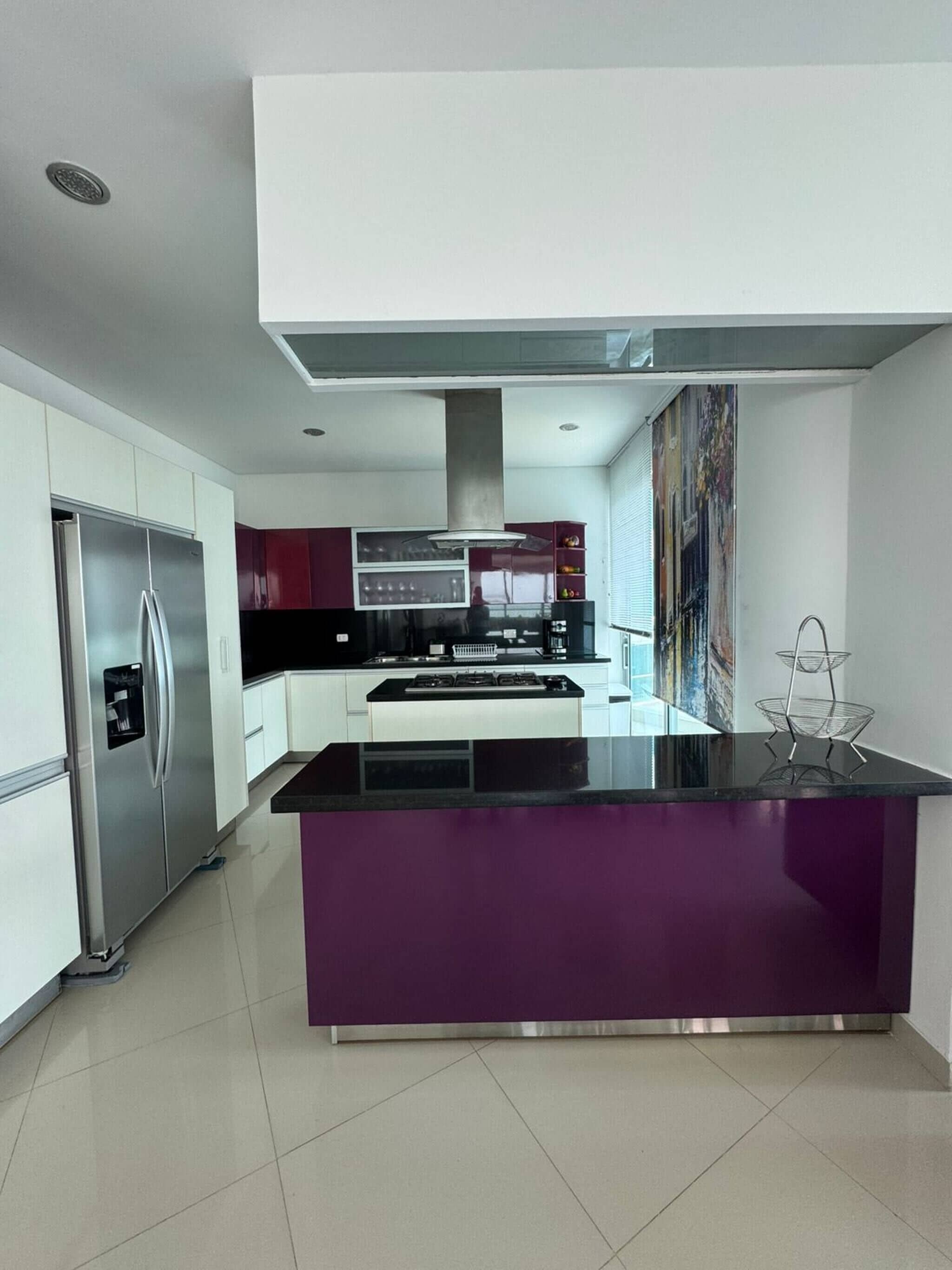 Una cocina moderna con una isla central, electrodomésticos de acero inoxidable y un amplio ventanal.