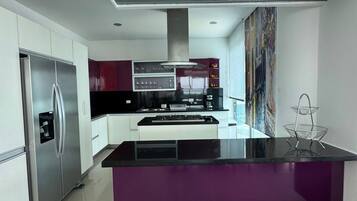 Una cocina moderna con una isla central, electrodomésticos de acero inoxidable y un amplio ventanal.