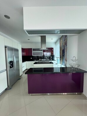 Una cocina moderna con una isla central, electrodomésticos de acero inoxidable y un amplio ventanal.