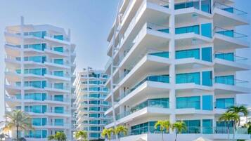 Un hotel moderno con varios balcones, piscina y palmeras.