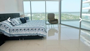 Una camera da letto moderna con un letto grande, una sedia e un balcone vista città.