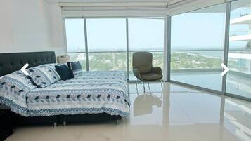 Un dormitorio moderno con una cama grande, una silla y un balcón con vistas a la ciudad.