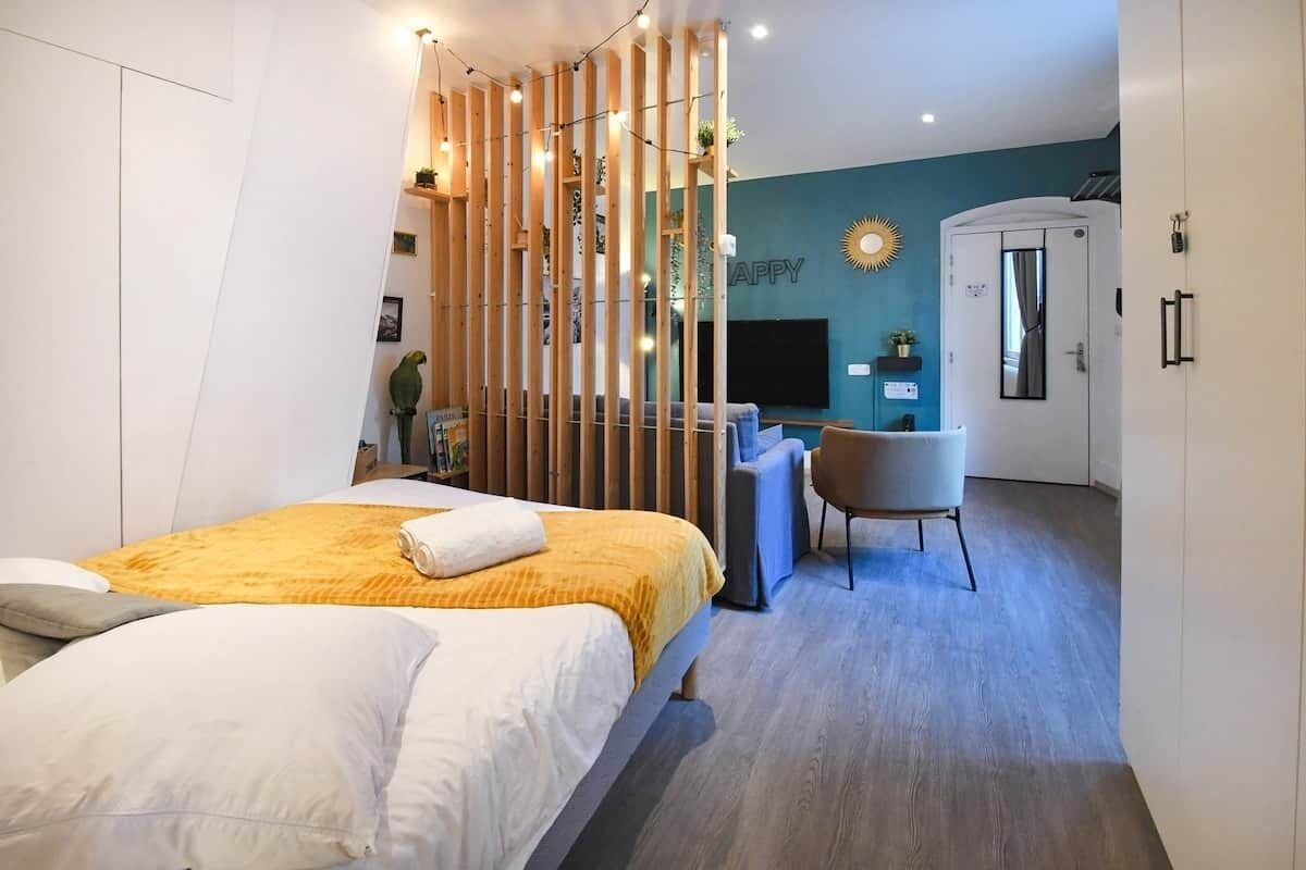 A modern hotel room with a bed, a desk, a chair, and a wardrobe.