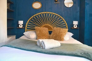 A bed with a unique headboard, two lamps on nightstands, and a blue wall. - At the Bretzel Doré - Historic District (Colmar)