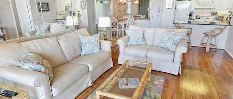 A spacious living room with two sofas, a coffee table, and a kitchen in the background.