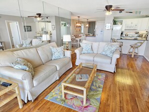 A spacious living room with two sofas, a coffee table, and a kitchen in the background. - Oceanfront 2 Bed 2 Bath Condo with Pool! Braemar Towers 1804 (Ocean City)