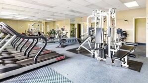 Un gimnasio con cintas de correr, máquinas de pesas y colchonetas de ejercicio.