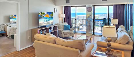 A living room with a sofa, armchairs, a TV, and a balcony with a view.