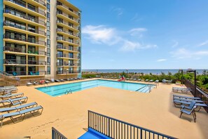 A hotel pool area with a clear view of the ocean, a multi-story building with balconies, and sun loungers. - Oceanfront 2 Bed 2 Bath Condo with Pool! Braemar Towers 1804 (Ocean City)