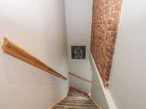 A staircase with wooden handrails, a brick wall, and a Buddha statue on the wall. - Barn 1 (Sandbach)