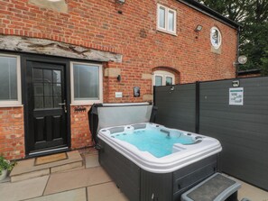 A brick house with a black door, a window with blinds, and a hot tub in the backyard. - Barn 1 (Sandbach)