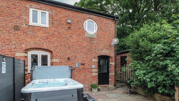 A brick building with a hot tub, a small garden, and a wooden gate. - Barn 2 (Sandbach)