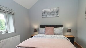 A bedroom with a bed, two bedside tables, a window with a view, and a wall-mounted artwork. - Barn 2 (Sandbach)