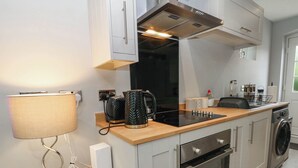 A modern kitchen with a built-in oven, a coffee maker, and a kettle on the countertop. - Barn 2 (Sandbach)