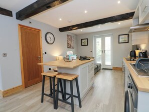 A kitchen with a wooden island, bar stools, a clock, and a door. - Barn 2 (Sandbach)