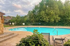 Ein Schwimmbad mit einer Steinmauer, einem Rettungsschwimmerstand und einem Stuhl.