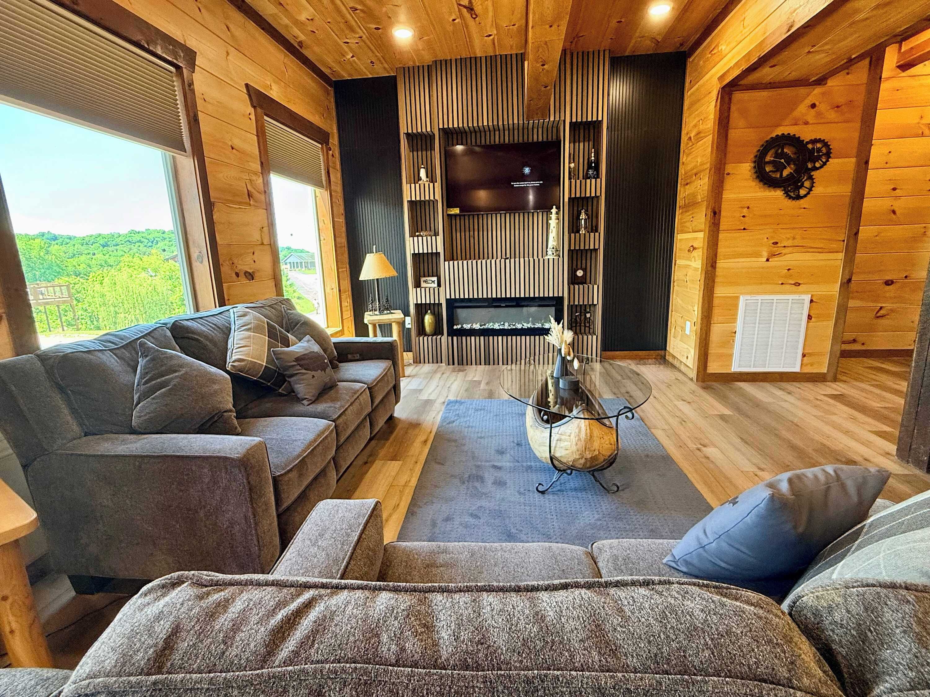 A cozy cabin interior with a wooden interior, a sofa, a coffee table, and a fireplace.