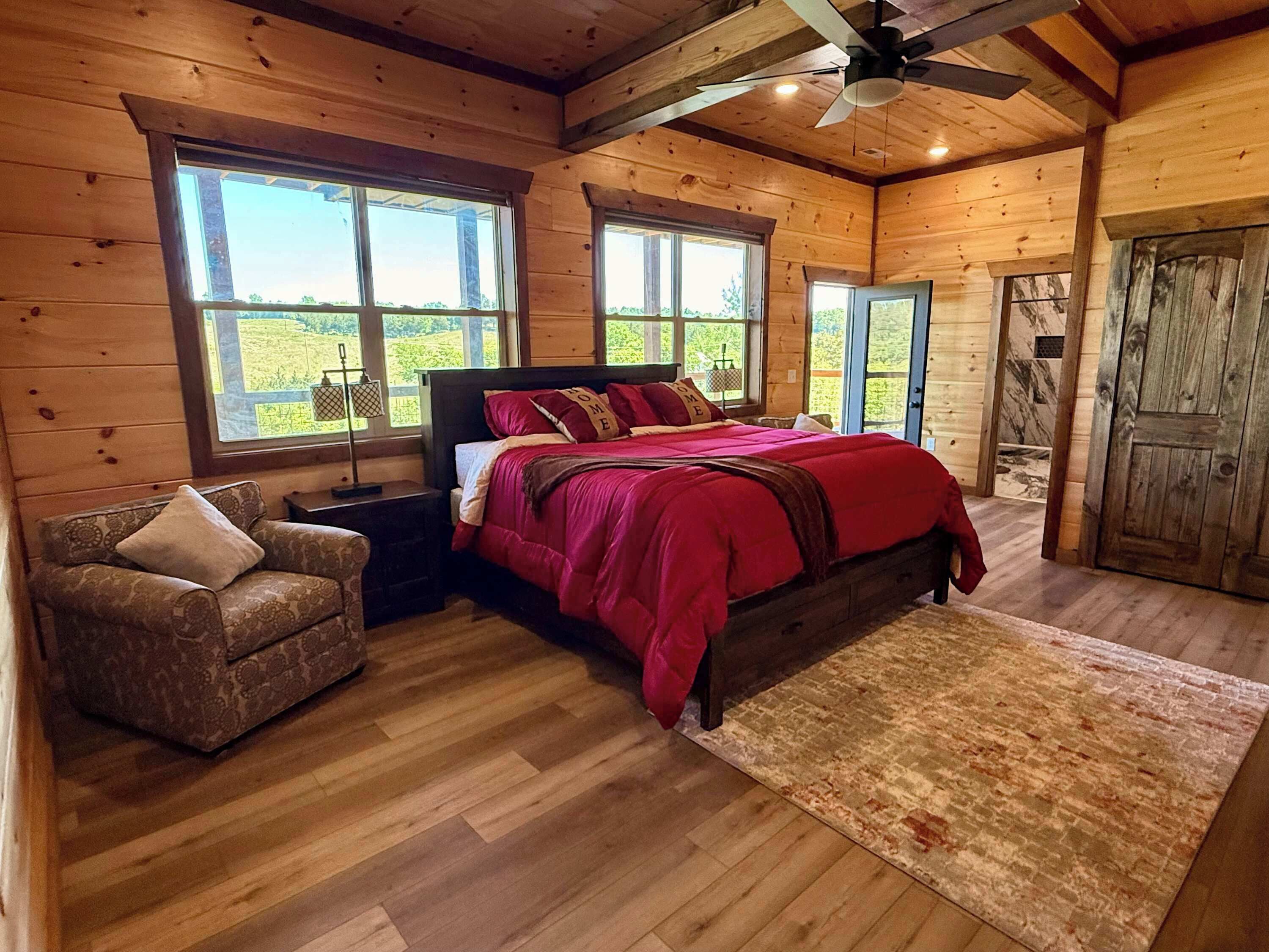 Une chambre dans une cabane en bois, avec un lit, une chaise et de grandes fenêtres.