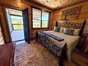 Ein Schlafzimmer einer Holzhütte mit Bett, Fenster und Tür nach draußen.
