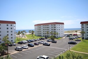 Ein Hotel mit Parkplatz, mehreren Etagen und Blick auf den Strand.