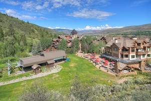 A mountain resort with chalet-style buildings, a ski lift, and outdoor seating areas.