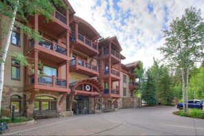 A multi-story building with balconies, stone facade, and a paved entrance area. - Premium Arrowhead Village 1br Condo Walk To Lift! 1 Bedroom Condo (Edwards)