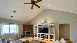 Una sala de estar con chimenea, televisor y ventilador de techo.