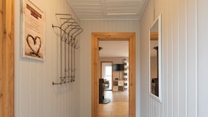 Um corredor com uma porta de madeira que dá para um quarto, um cabideiro e um cartaz na parede.