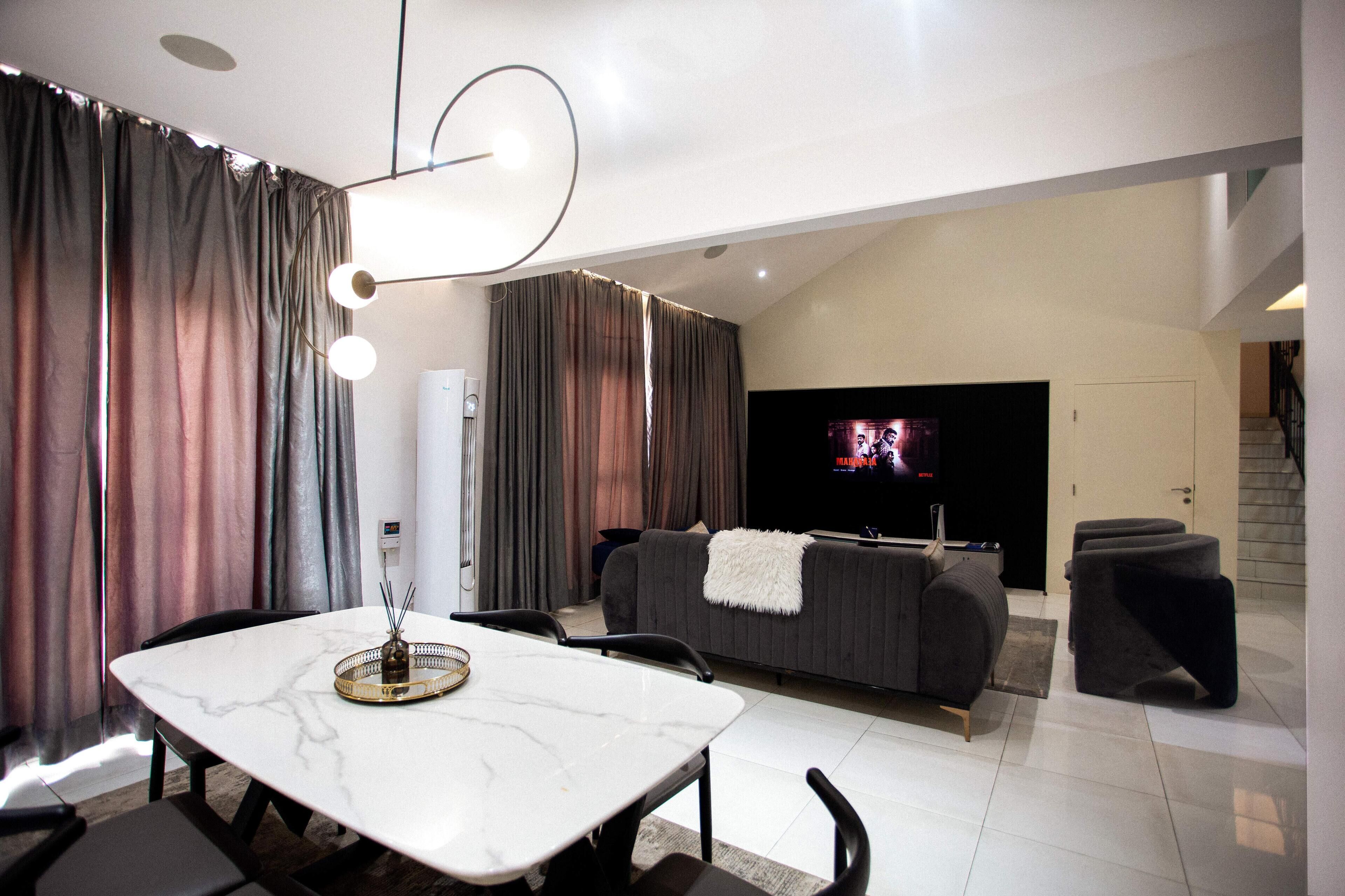 Uma sala de estar moderna com uma mesa de jantar, sofá e televisão de tela plana.