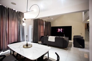 Uma sala de estar moderna com uma mesa de jantar, sofá e televisão de tela plana.