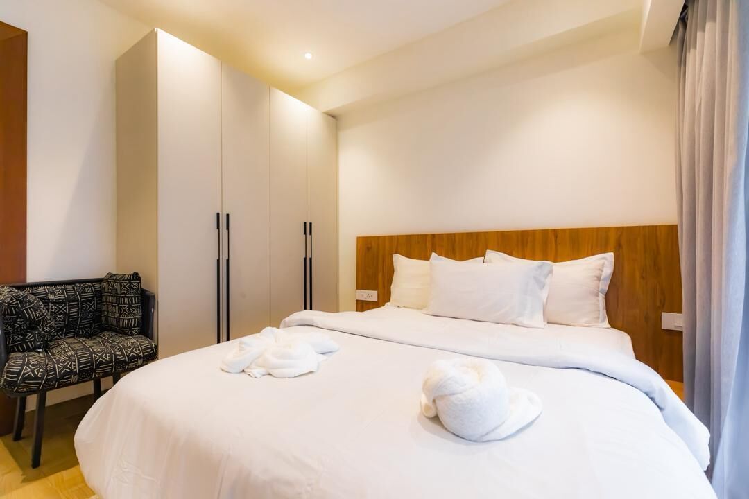 Une chambre d’hôtel avec un grand lit, une tête de lit en bois, une armoire et une chaise à motifs.