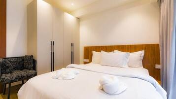 A hotel room with a large bed, a wooden headboard, a wardrobe, and a patterned chair.
