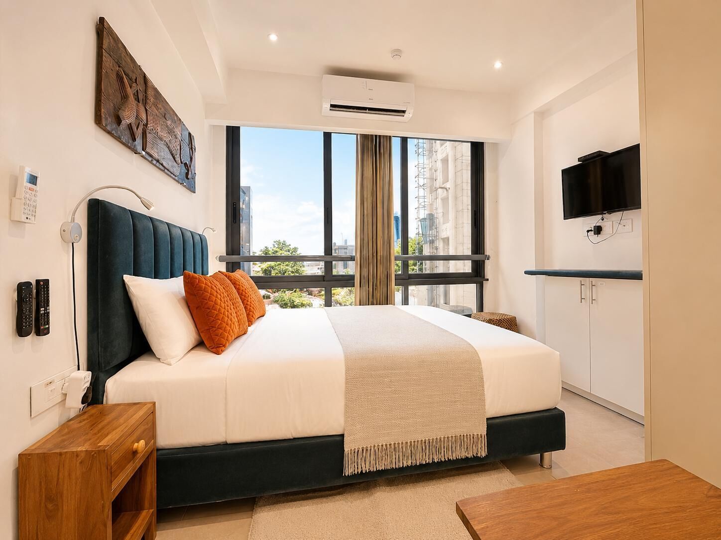 A modern hotel room with a large bed, a television, and a view of the city.