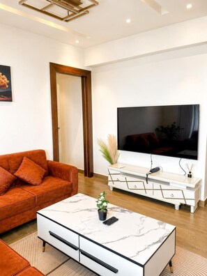 A modern living room with a sofa, coffee table, TV, and a cabinet. - Solaris  (Accra)