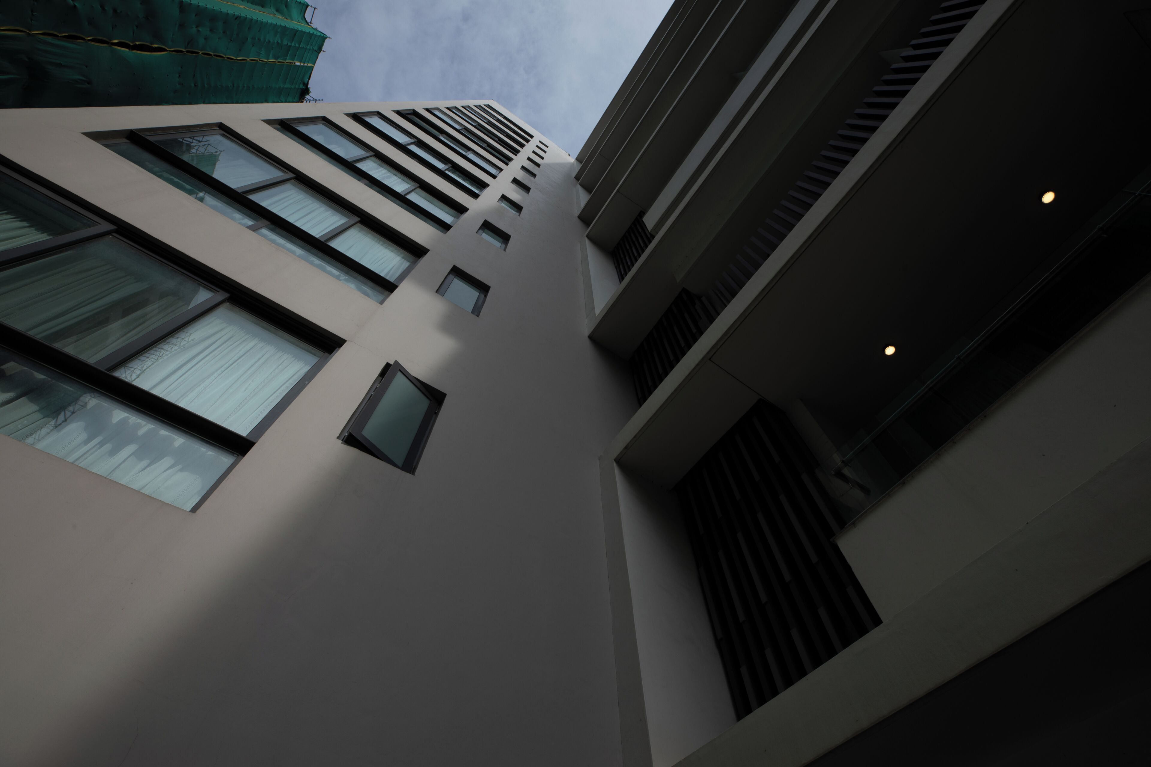 Un edificio de varios pisos con un diseño arquitectónico moderno, que cuenta con una serie de ventanas y una escalera visible.