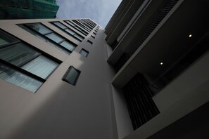 Ein mehrstöckiges Gebäude mit moderner Architektur, das eine Reihe von Fenstern und eine sichtbare Treppe aufweist.