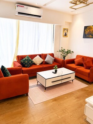 Ein modernes Wohnzimmer mit einer Sofagarnitur, einem Couchtisch und einer Klimaanlage.