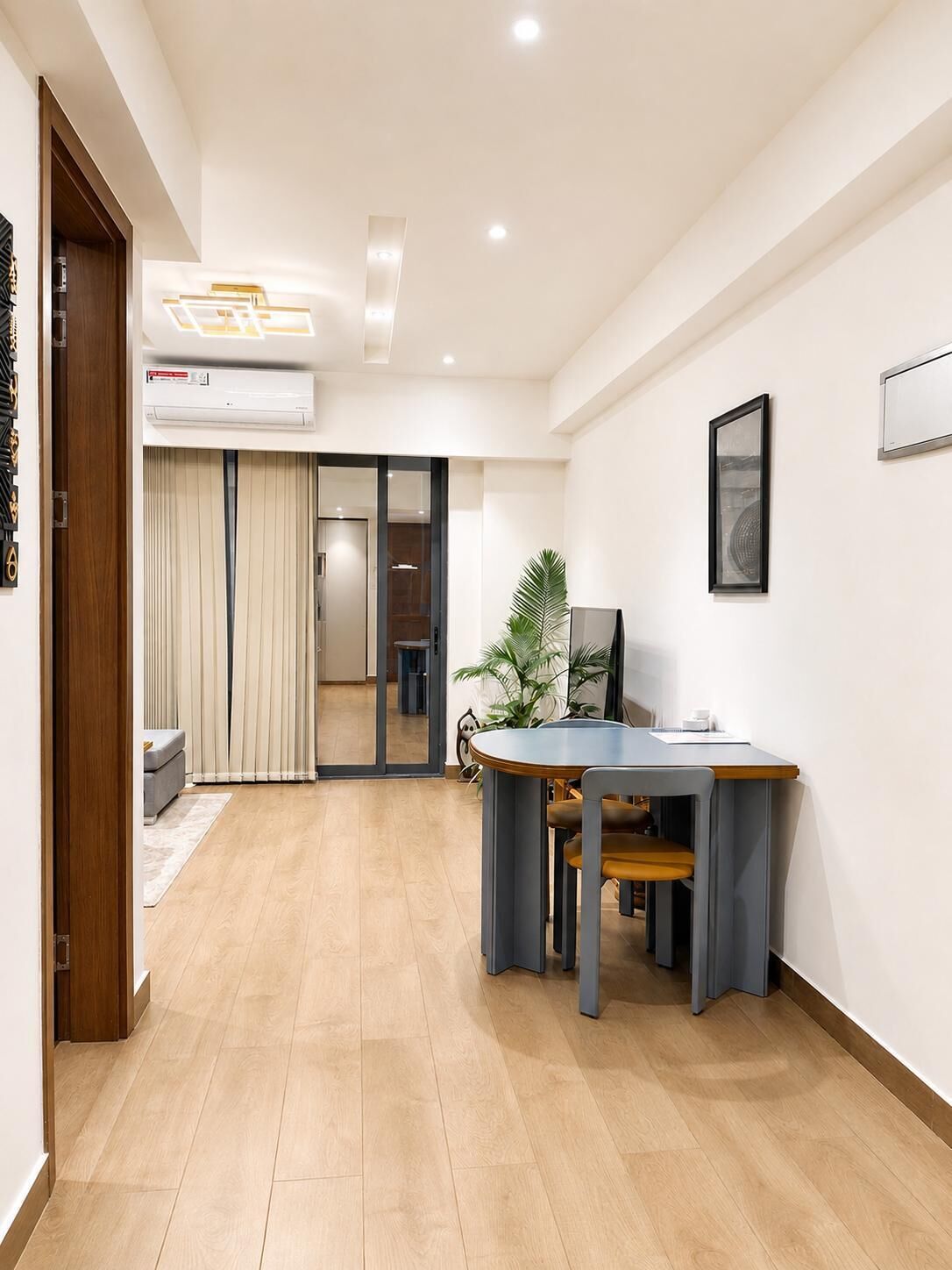 Un intérieur moderne avec un plancher en bois, un bureau avec des chaises, une plante en pot et un tableau encadré au mur.