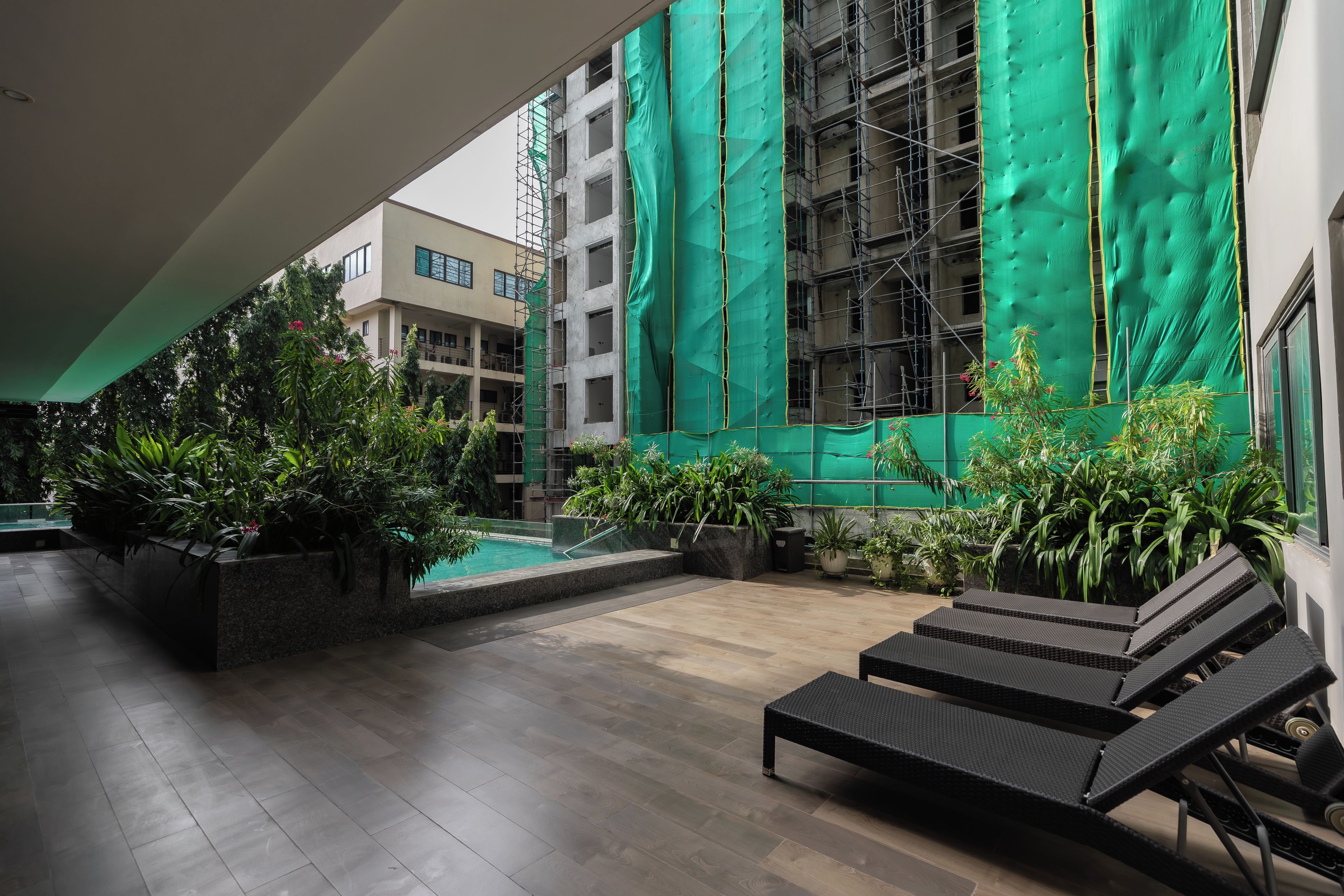 Un espace extérieur abrité comprenant une piscine, des chaises longues et des plantes en pot.