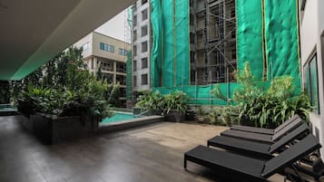 Un espace extérieur abrité comprenant une piscine, des chaises longues et des plantes en pot.