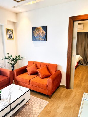 A living room with a sofa, a coffee table, and a painting on the wall. - Solaris  (Accra)