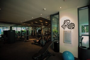 A gym with various exercise equipment, a wall-mounted sign, and a window providing a view of the outdoors. - Solaris  (Accra)